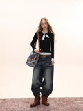 Full body shot of a model in a black long-sleeve top, distressed denim jeans, and brown boots