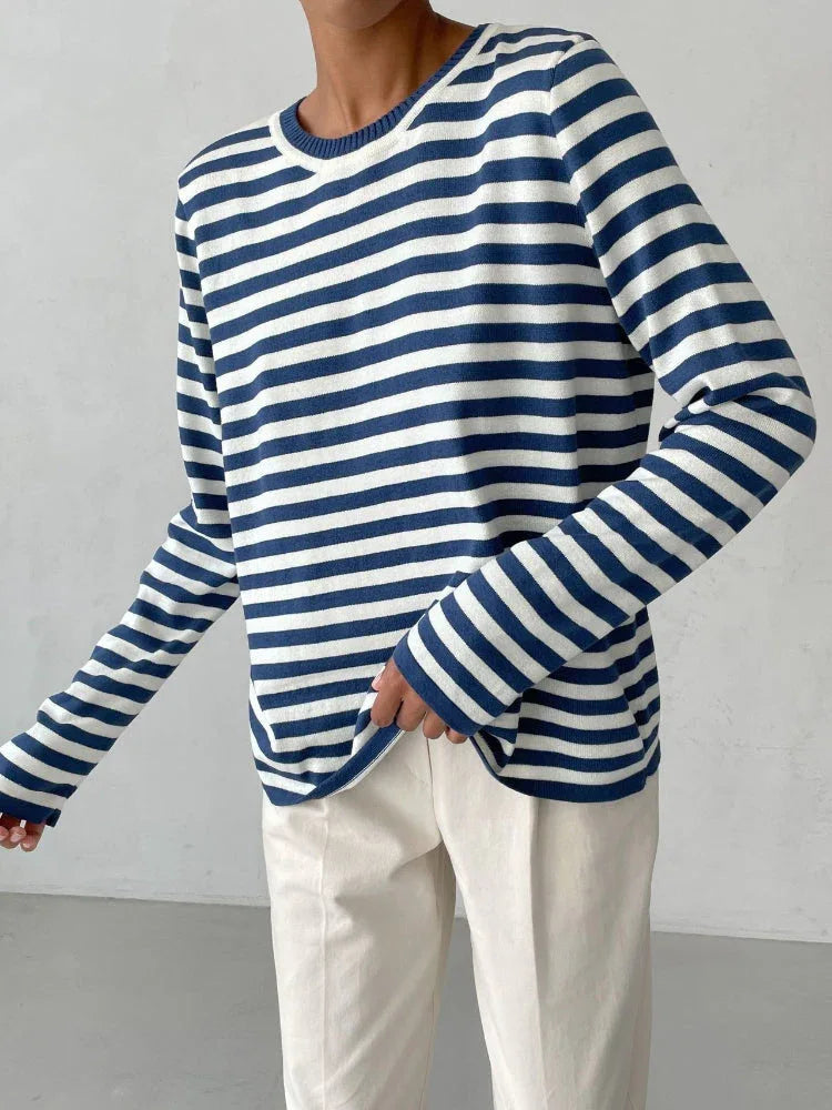 Close-up of a woman wearing a blue and white striped long-sleeve top and cream trousers.