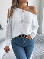 Woman with hand in pocket, wearing a white off-the-shoulder knit sweater and blue jeans