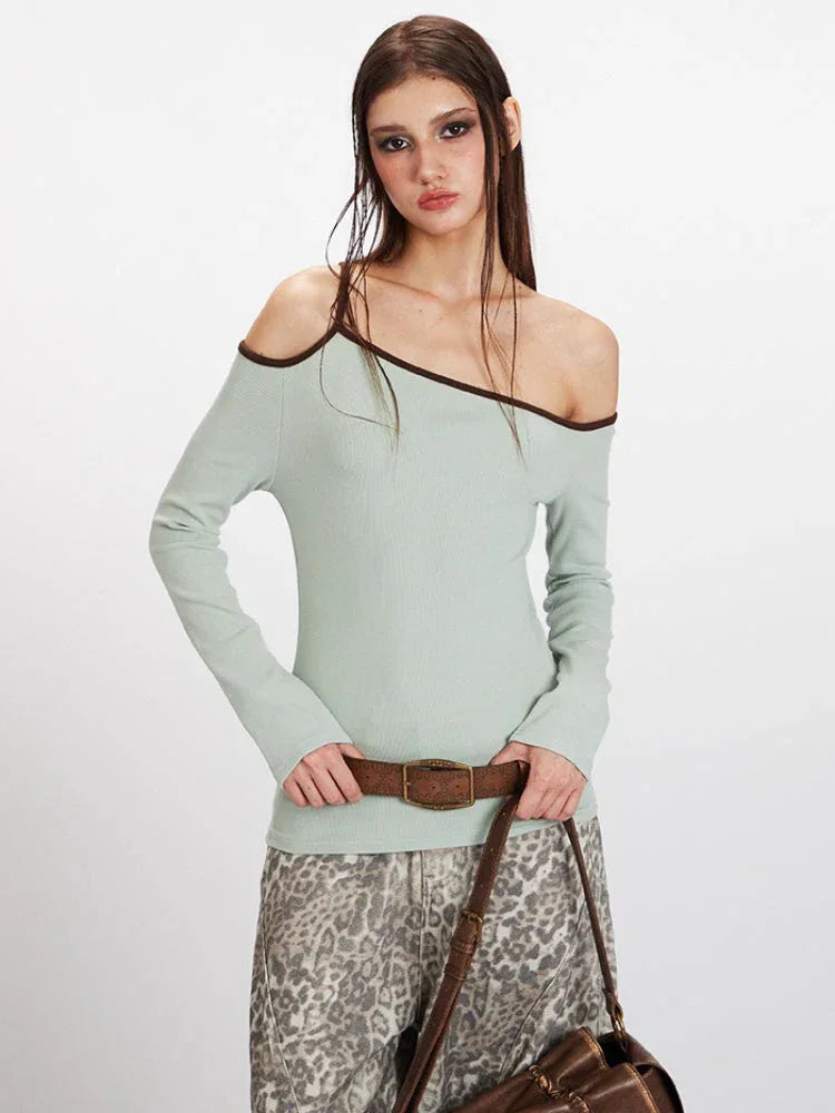 Close-up of a model showcasing the asymmetrical neckline and contrast trim of a light green ribbed knit top.