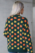 Back view of a woman wearing a dark green knit sweater with an orange and yellow leaf print.