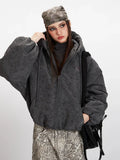 Close-up of a woman's face and shoulders wearing a charcoal grey textured puffer jacket.