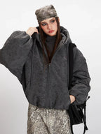 Close-up of a woman's face and shoulders wearing a charcoal grey textured puffer jacket.