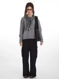Woman wearing a grey crew neck sweater with black cargo pants and a striped scarf