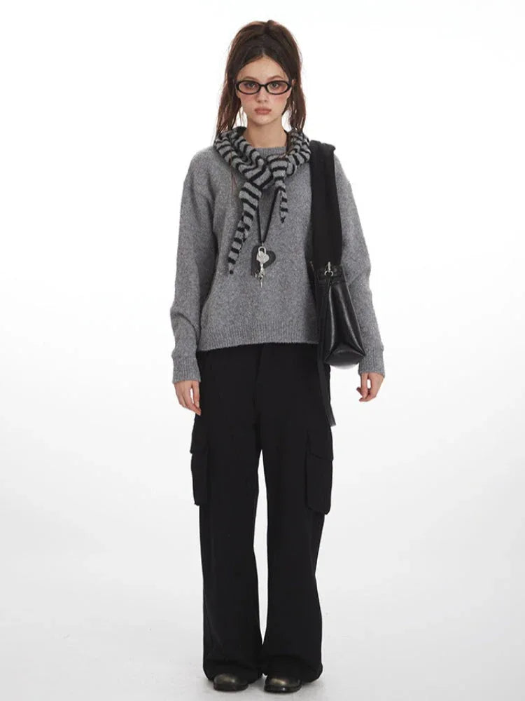 Woman wearing a grey crew neck sweater with black cargo pants and a striped scarf
