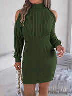 Woman holding a gold chain purse, wearing a green cold shoulder knit dress