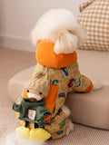 Rear view of a small white dog in a yellow patterned dog jacket with a teddy bear applique on the back.