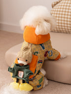 Rear view of a small white dog in a yellow patterned dog jacket with a teddy bear applique on the back.