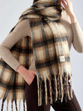 Woman adjusting a fluffy plaid scarf with pink and brown colors