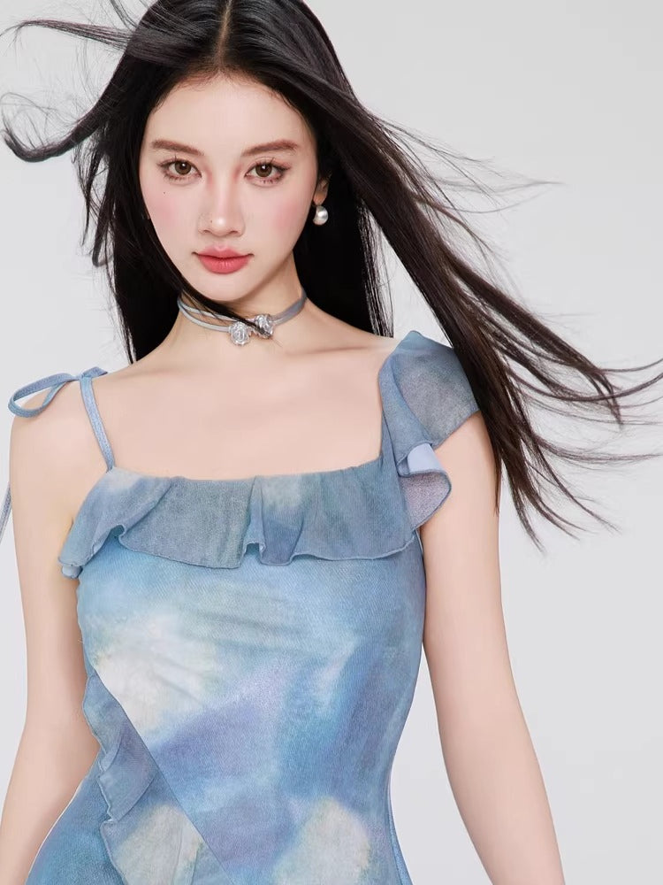 Woman wearing a blue tie-dye print mini dress with ruffle trim and tie shoulder straps