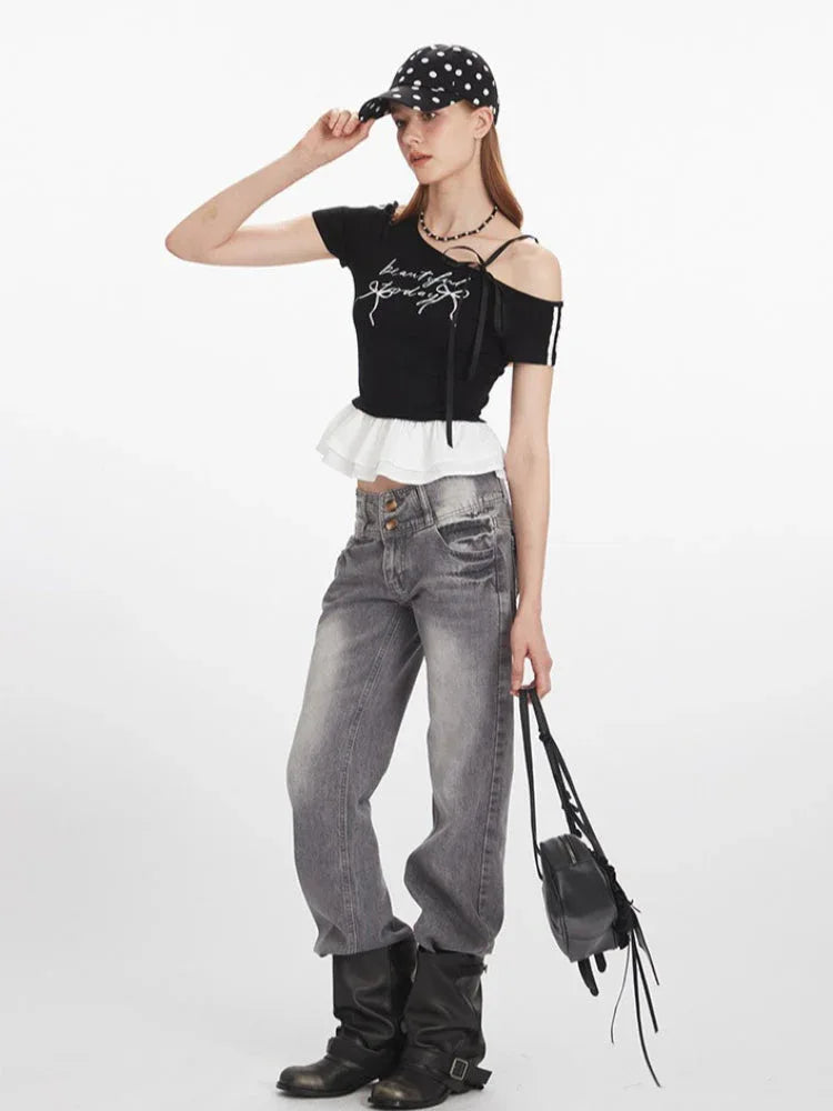 Full body shot of a woman in a black cropped t-shirt, grey jeans, and a polka dot cap, holding a black handbag.