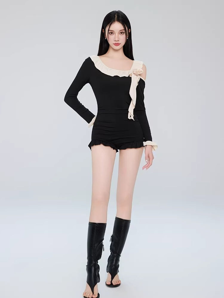 Woman wearing a navy blue one-piece swimsuit with light blue ruffle trim and a white sheer cardigan