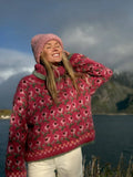 Close-up of a woman wearing a pink floral knit turtleneck sweater and pink beanie