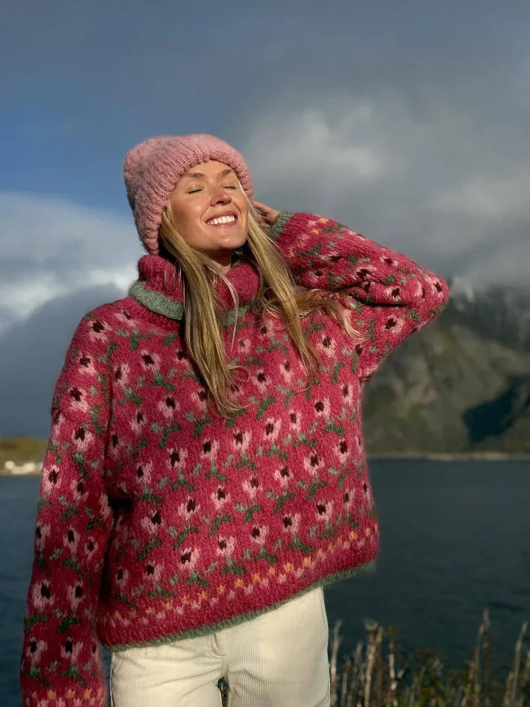 Close-up of a woman wearing a pink floral knit turtleneck sweater and pink beanie