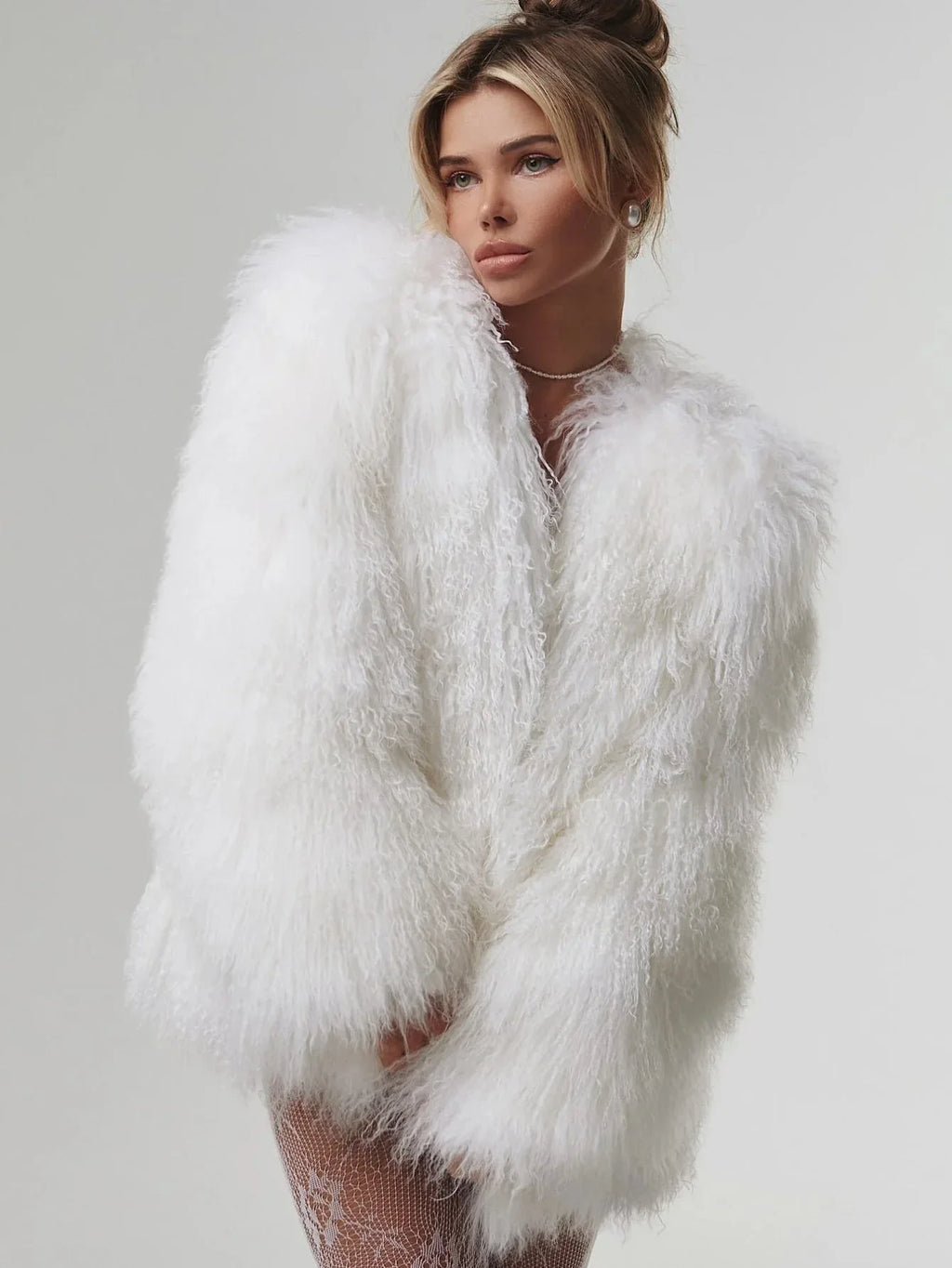 Woman wearing a white faux fur coat with a textured appearance.
