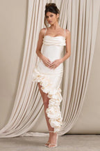 Front view of a woman in a cream satin special occasion dress with ruched detailing and a dramatic ruffle cascade.