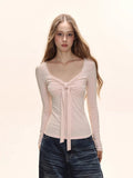 Model wearing a light pink long sleeve tie front top
