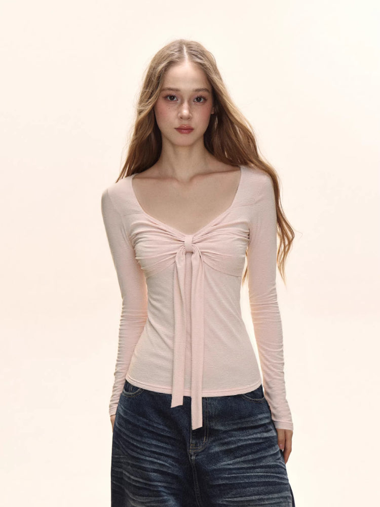 Model wearing a light pink long sleeve tie front top