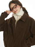 Close-up of the collar and neckline of a brown corduroy bomber jacket worn by a woman.