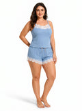 Woman in a light blue ribbed knit camisole and shorts set with white lace trim, standing with her hand on her hip.