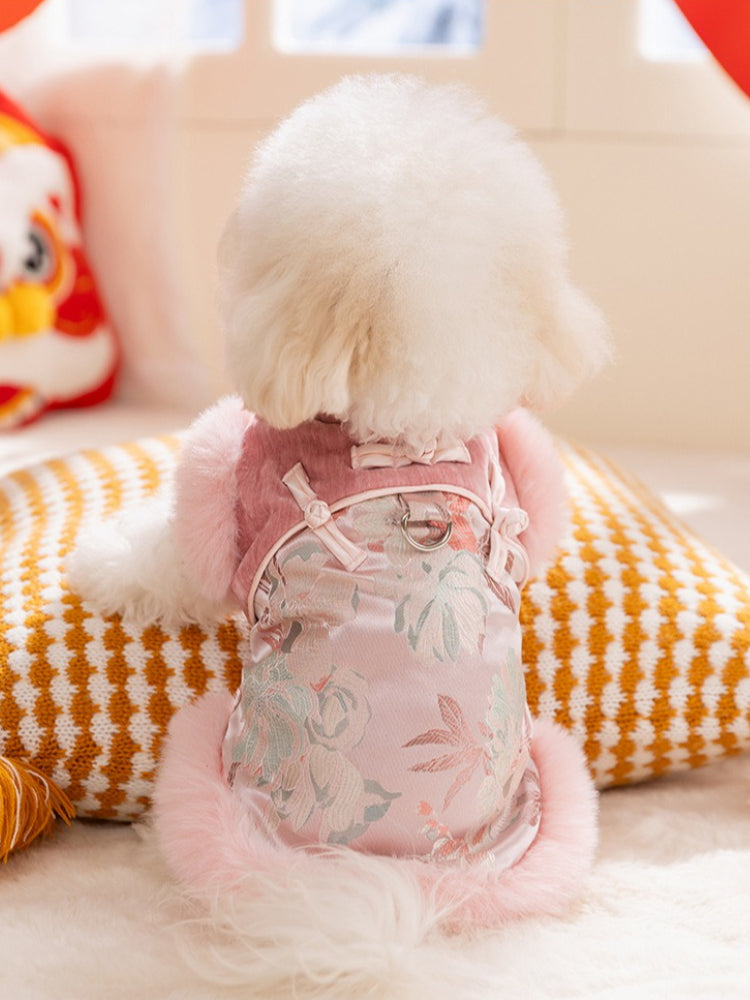 Back view of a white dog wearing a pink and white traditional Chinese style dog jacket with floral embroidery and pink faux fur trim.