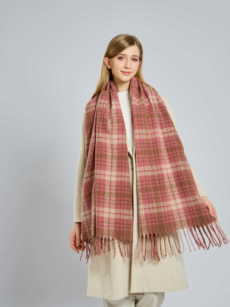 Full shot of a woman modeling a large plaid scarf in pink and beige tones.