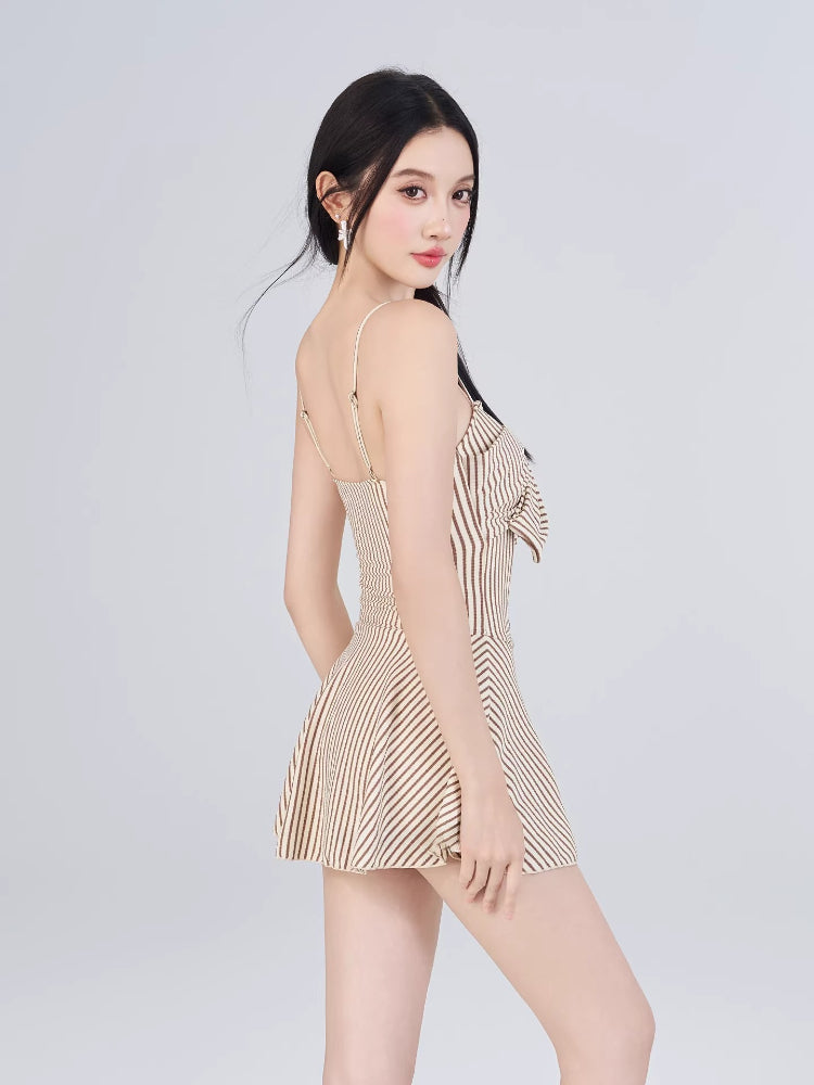 Woman in a striped fit and flare dress with a bow detail, side view.