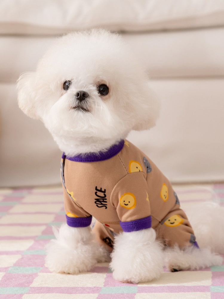 Side view of a small white dog in a tan dog pajama with purple trim