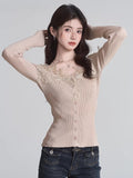 Woman wearing a beige fitted ribbed knit cardigan with lace trim and button-down front, adjusting her hair