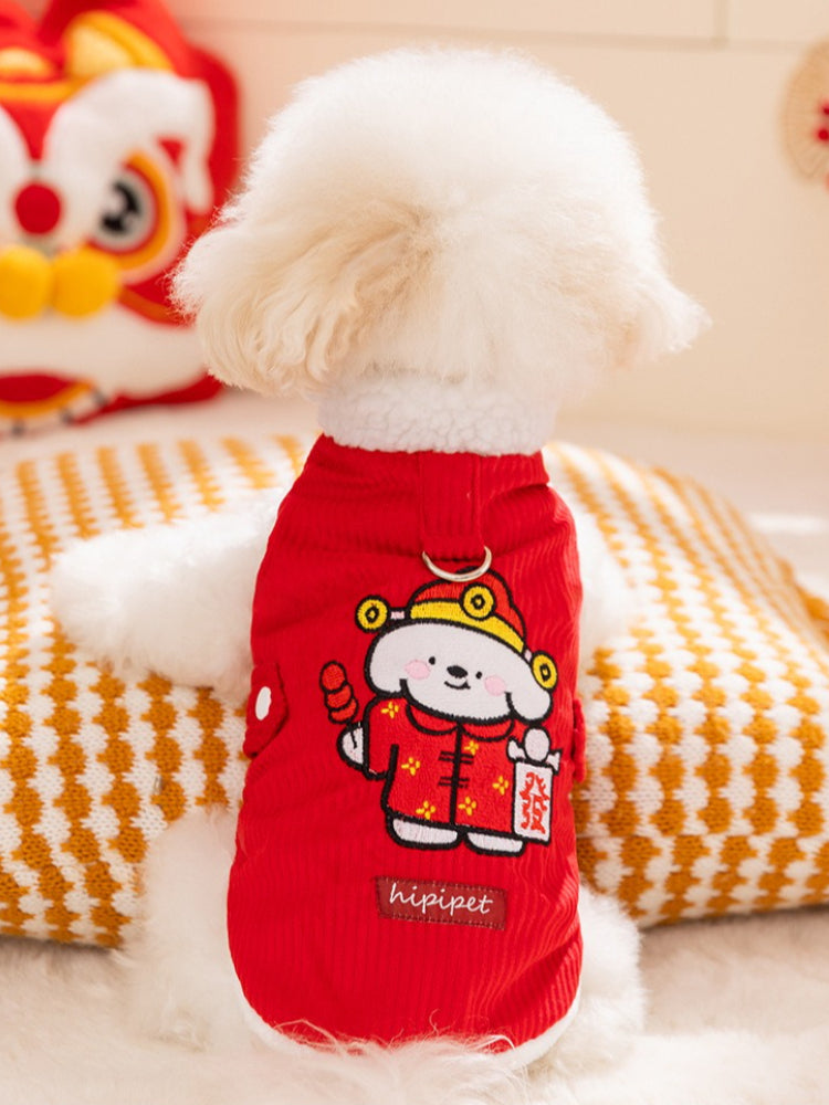 A white Bichon Frise dog wearing a red corduroy pet vest with white sherpa lining and two white buttons.