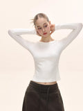 Woman adjusting her hair, showcasing the white long-sleeve fitted top.