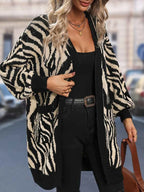 Woman adjusting her zebra print cardigan, showcasing the open front and long sleeves.