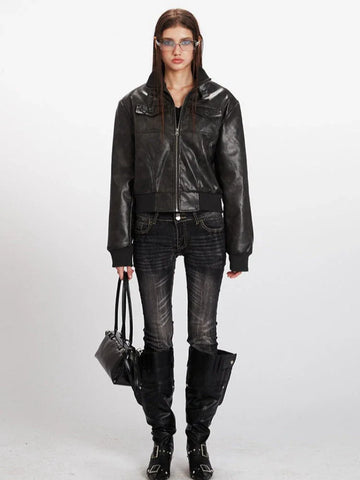 Woman wearing a black faux leather bomber jacket with zipper closure and chest pockets, black jeans, and black boots.