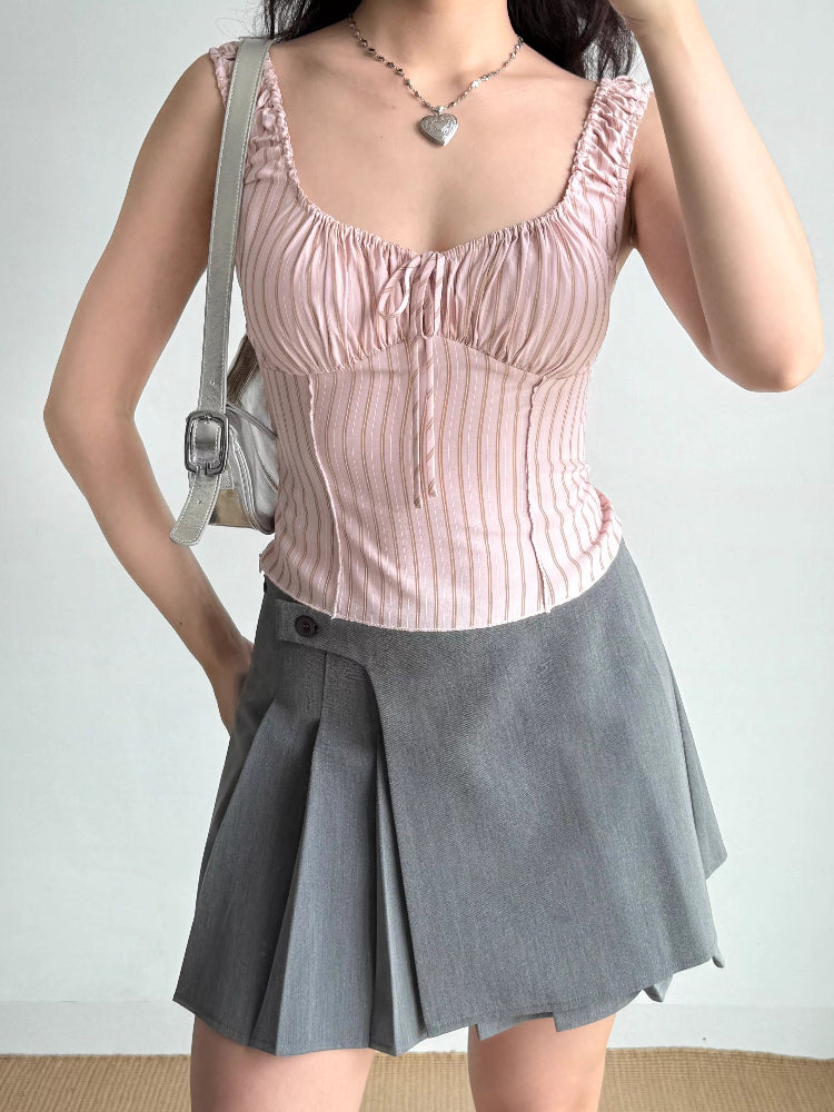 Woman wearing pink striped ruched tank top with grey skirt and silver handbag