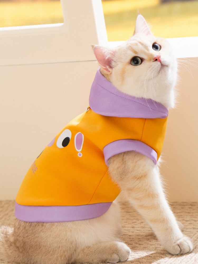 Side view of a cat wearing a yellow and purple hooded pet vest.