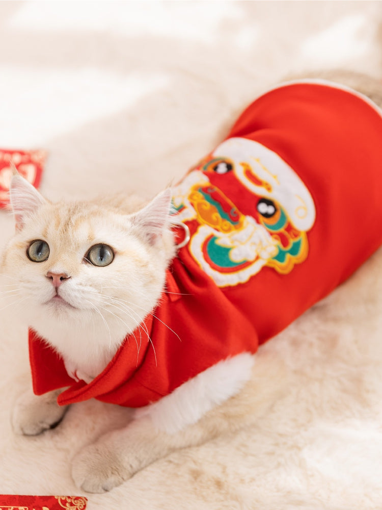 A white cat lying down wearing a red pet Tang suit vest with embroidered details