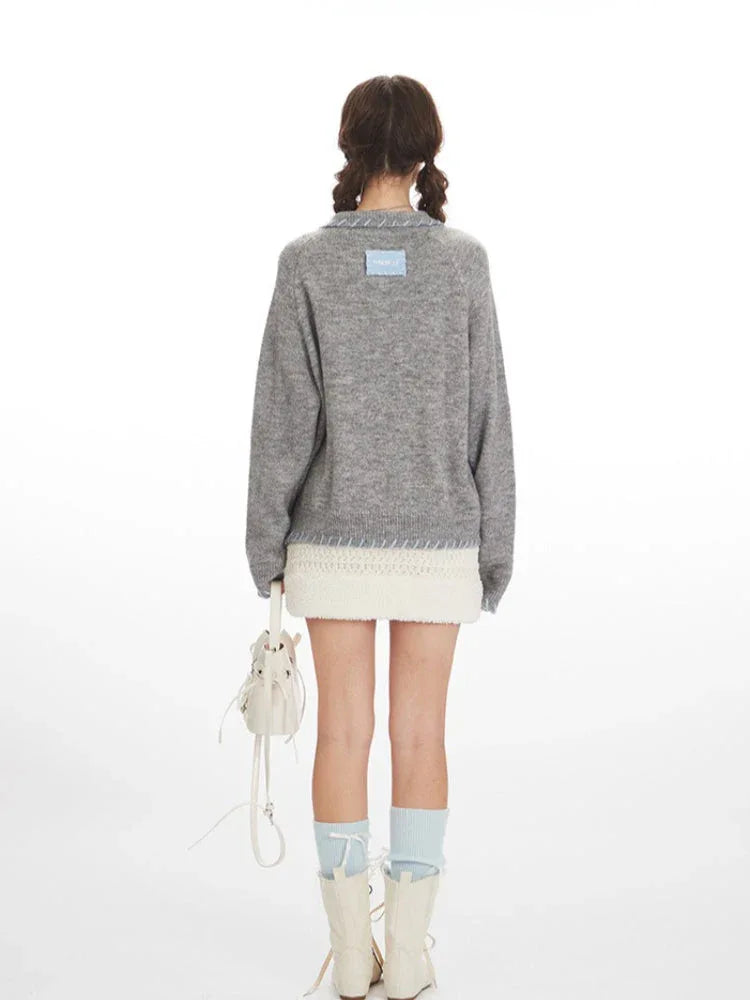 Back view of a grey knitted cardigan with white buttons and blue contrast trim