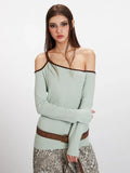 Model posing with arms crossed, highlighting the fitted silhouette and one-shoulder design of the light green top.