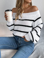 Woman wearing a white and black striped off-the-shoulder knit sweater with blue jeans, holding a coffee cup