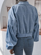 Back view of a woman in a light blue corduroy jacket, highlighting the balloon sleeves and cropped fit.