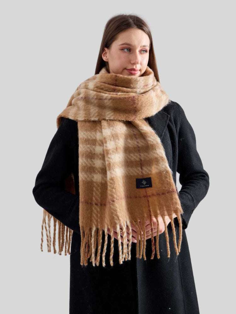 Woman wearing a tan and cream plaid scarf with fringe