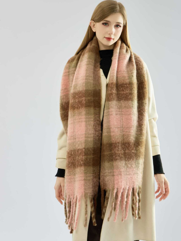 Woman with long blonde hair wearing a cream coat and a large plaid scarf.