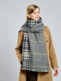 Woman styling a large plaid scarf draped over her shoulders.