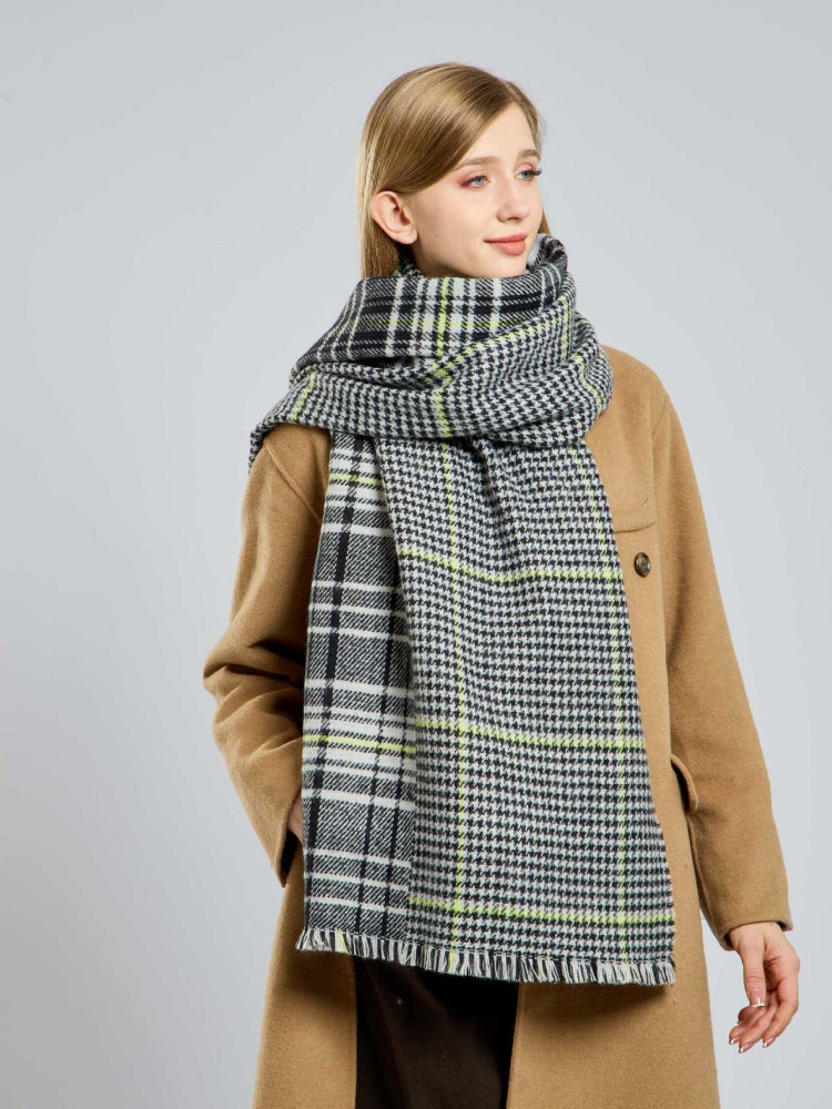 Woman styling a large plaid scarf draped over her shoulders.