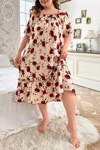 Plus-size woman wearing a cream-colored short-sleeve nightgown with a red floral print and ruffled hem, standing in a bedroom.