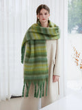 Model showcasing a large, soft green striped scarf with tassels