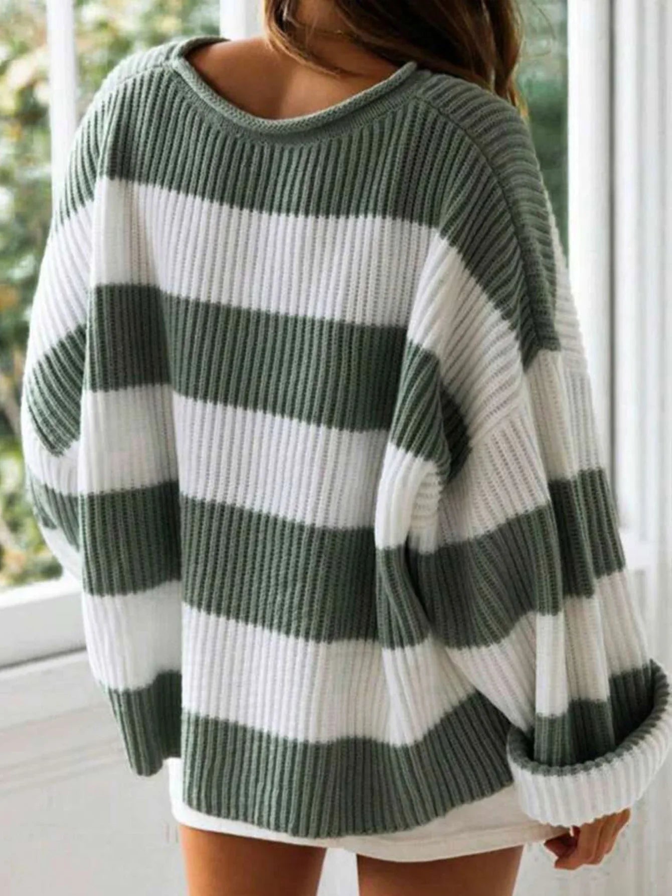 Back view of a woman in a green and white striped oversized knit sweater with crew neck.