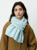 Close-up of a woman's face with a light blue knit scarf
