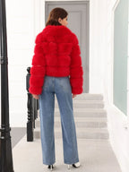 Rear view of a woman in a red faux fur jacket, highlighting the cropped silhouette and long sleeves.