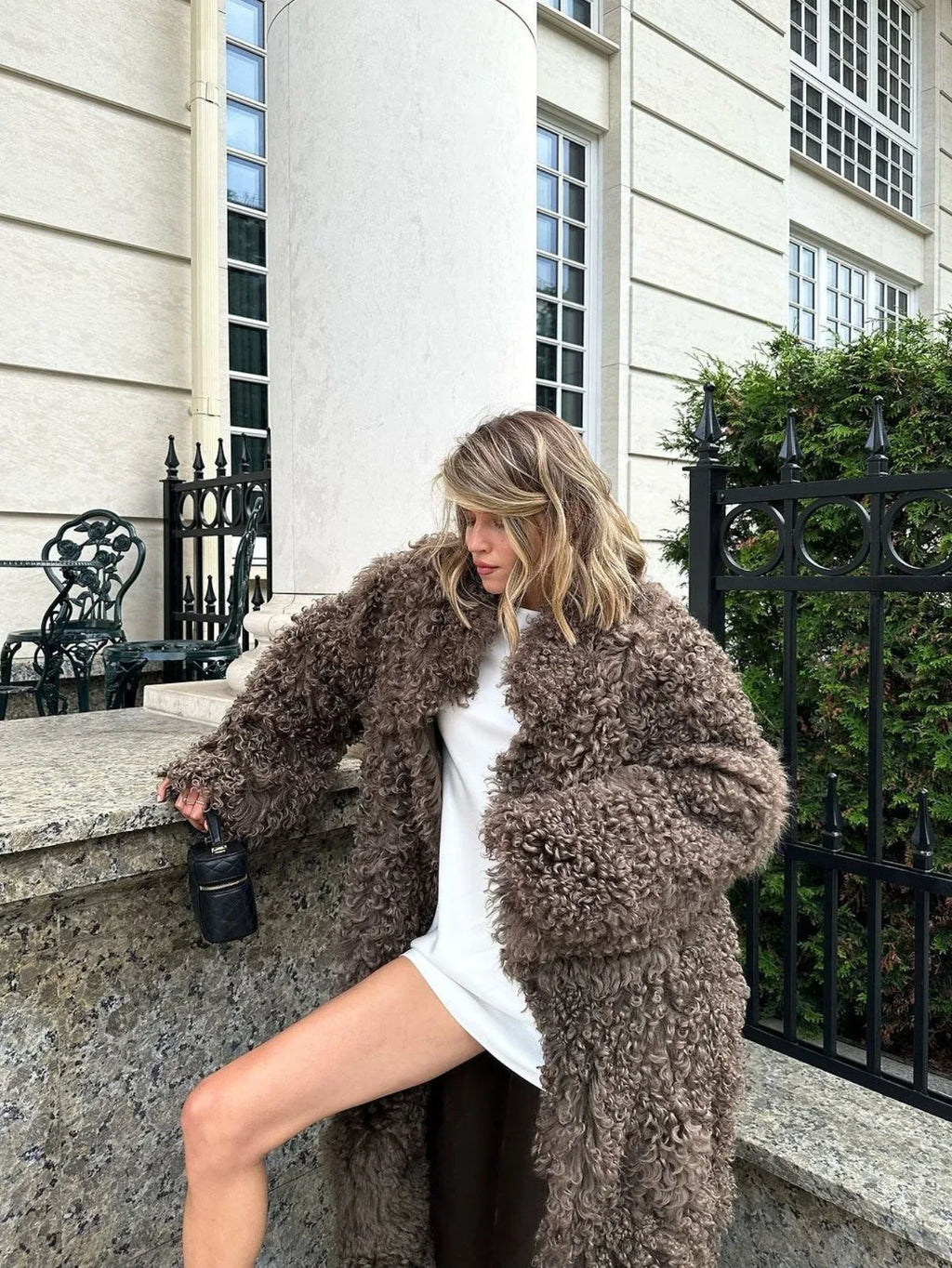 Full-length shot of a woman in a long brown faux fur coat.
